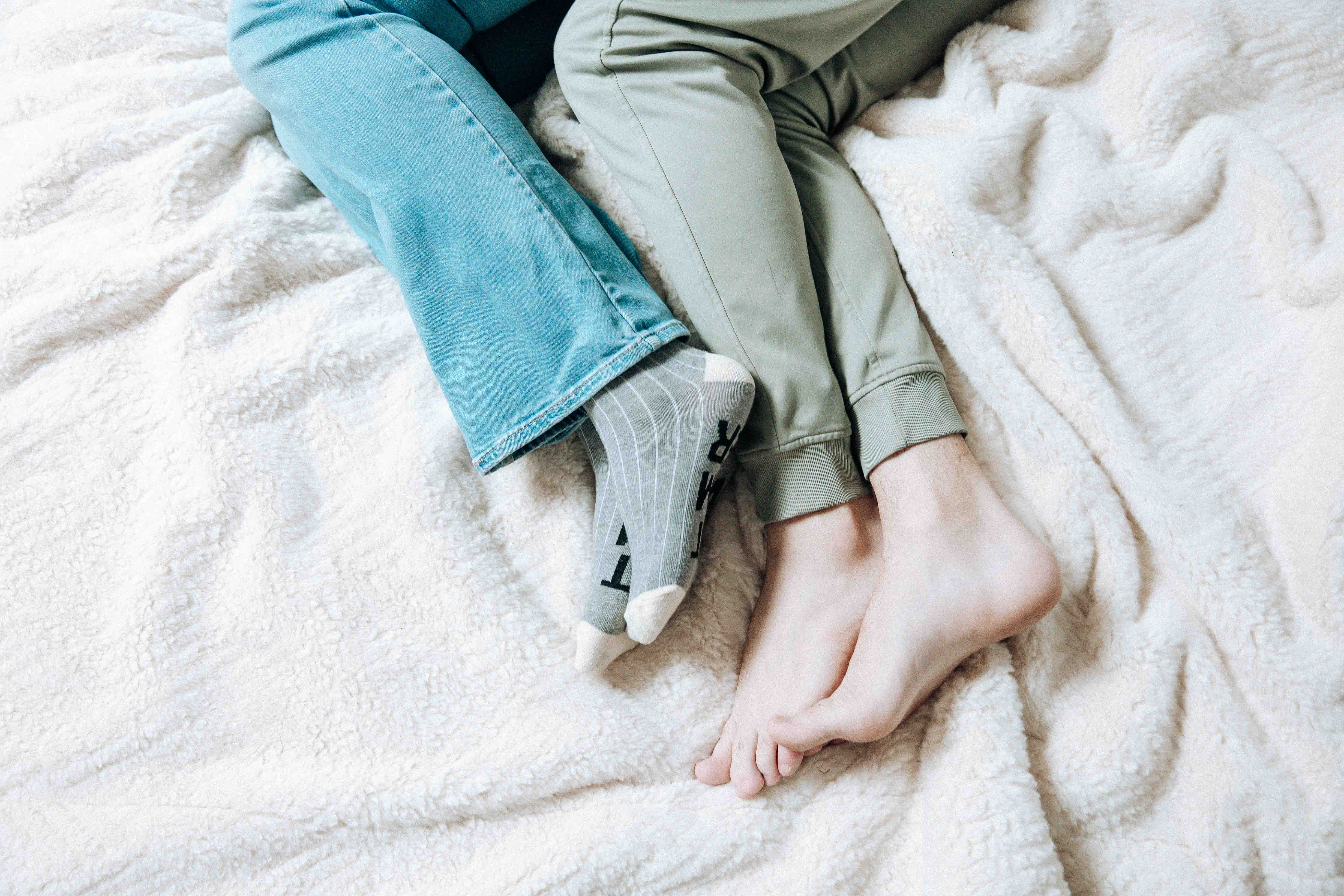 Two pairs of feet resting on a soft blanket